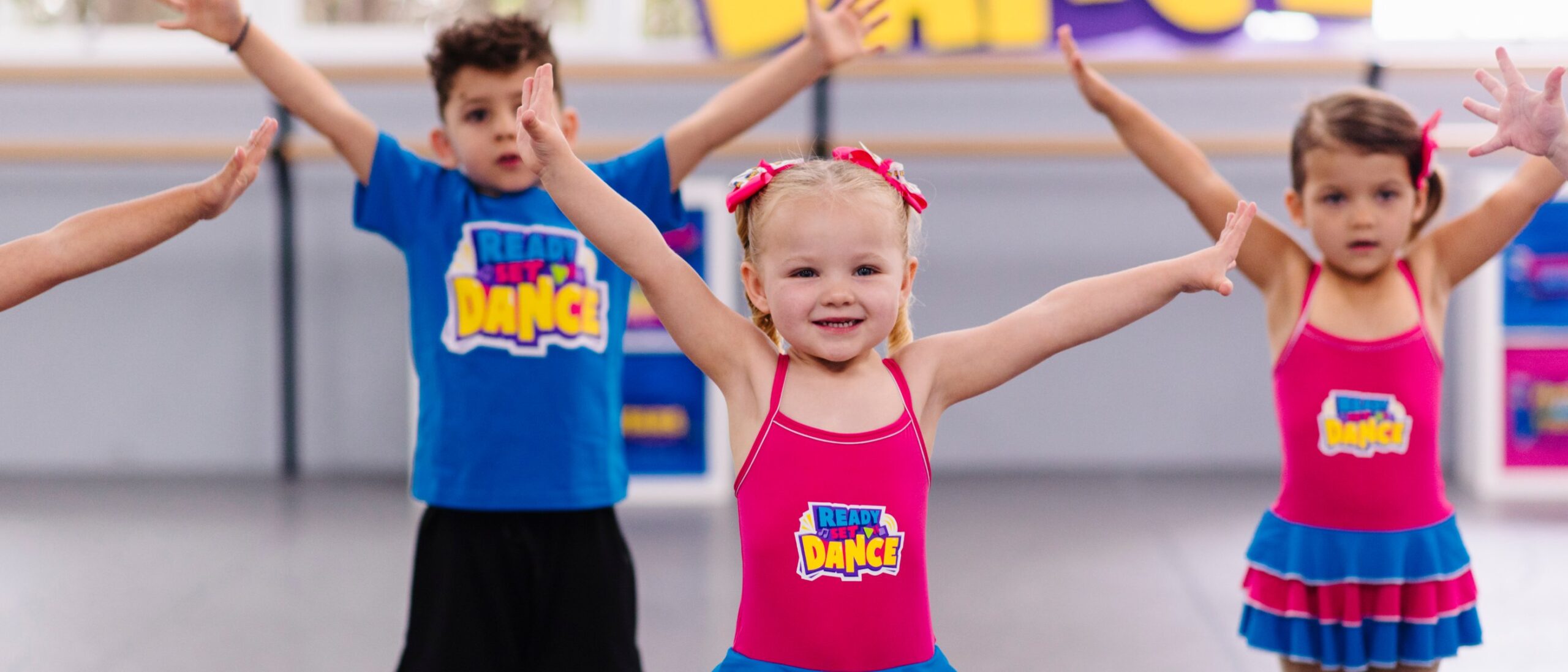 Preschool dancers in Ready Set Dance uniforms reaching up in class